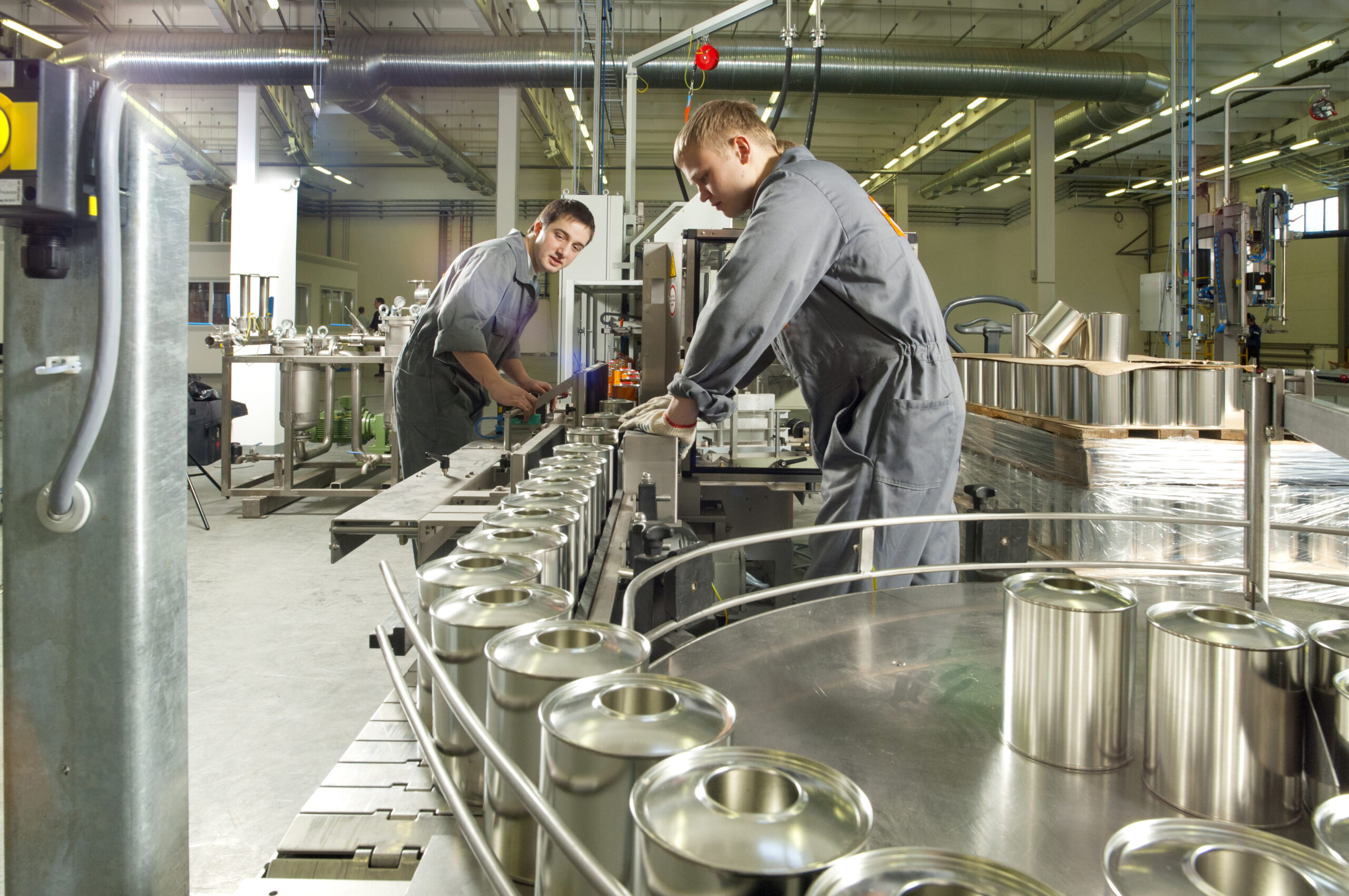 Two young workers working on an assembly line at a paint and varnish factory